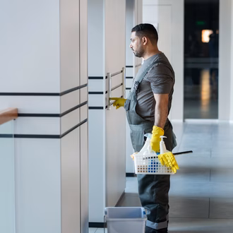 Reinigungskraft drückt Knopfe für den Lift