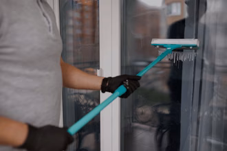 Mann reinigt ein Fenster mit einfacher Ausrüstung
