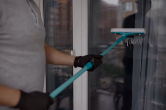 Ein Mann reinigt mit einfacher Ausrüstung eine Fensterfront