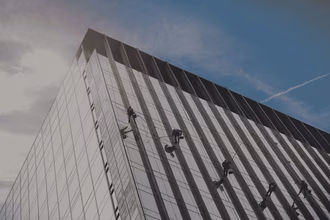 5 angeseilte Personen putzen gemeinsam eine grosse Fassade