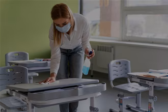 Reinigunskraft putzt ein Klassenzimmer gründlich